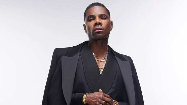 Kirk Franklin in a black suit against a white backdrop